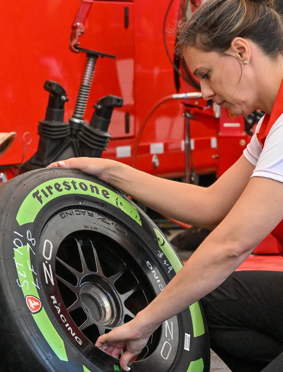 A technician carefully inspects and marks a Firestone racing tire.