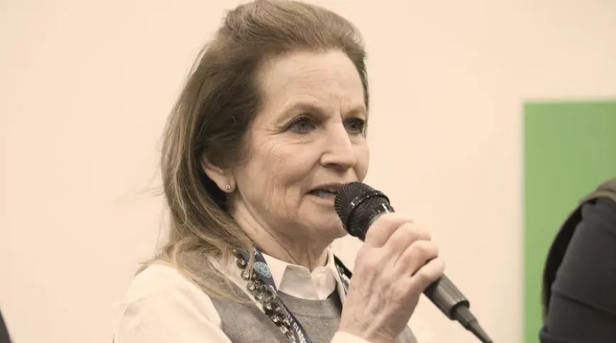 A woman speaking into a microphone during an event, shown in close-up.