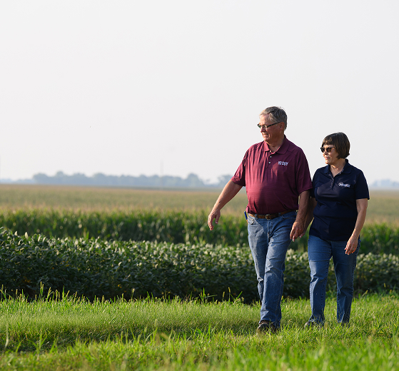 couple walking in front of farm crops